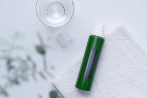 Green AirlessMotion® bottle with a viewing window for the inner pouch resting on a white towel.