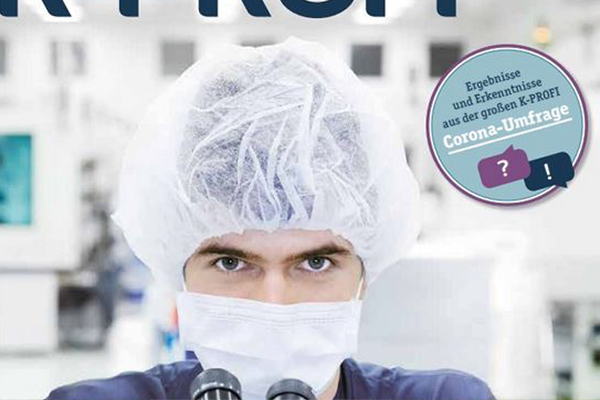 Person vor Mikroskop mit Haarnetz und Maske