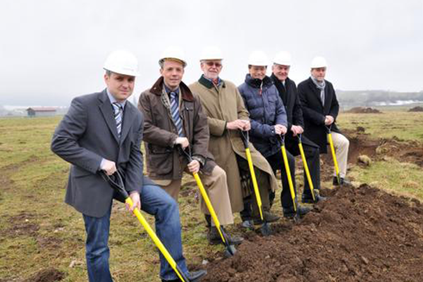 6 Personen mit Spaten und Bauhelm zum Spatenstich Neubau Firmengebäude in Peiting