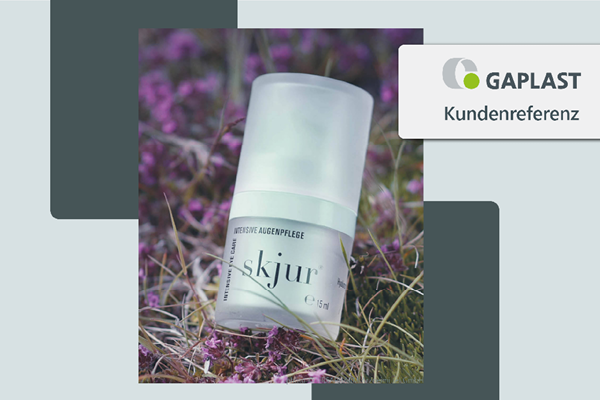 Produktfoto Skjur Intensive Augenflege mit Airless Glas Flasche auf Gras mit lila Blüten